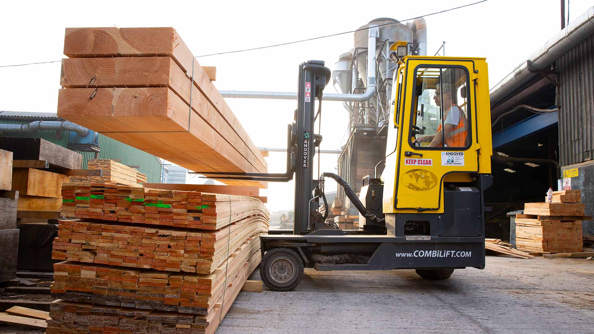 Large planks of wood being stacked up by forklift truck